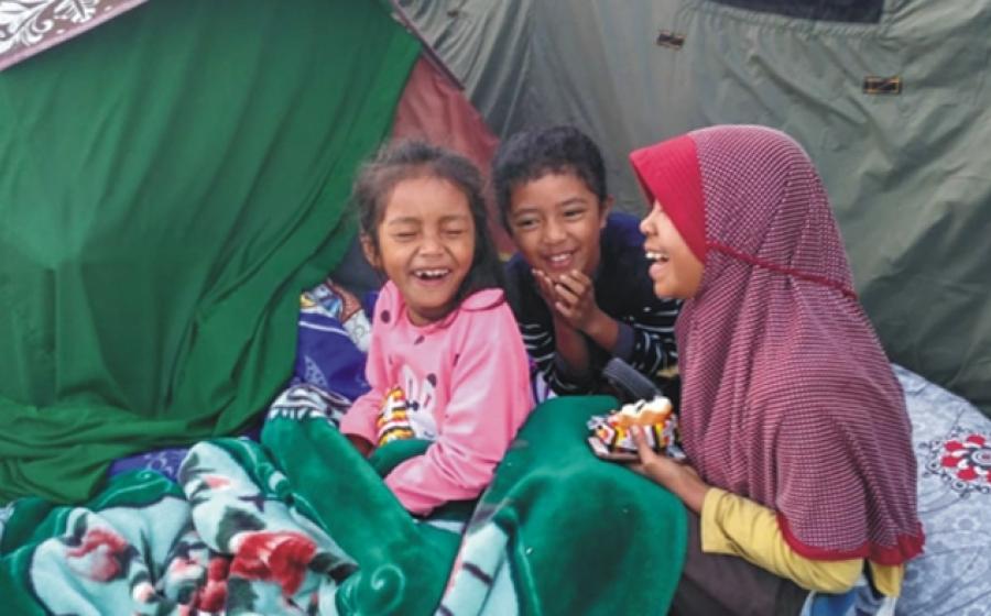 Foto tiga anak kecil yang sedang tertawa